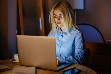 Young beautiful blonde girl working at laptop at home. Freelance, online business seminar, distant job or learning concept