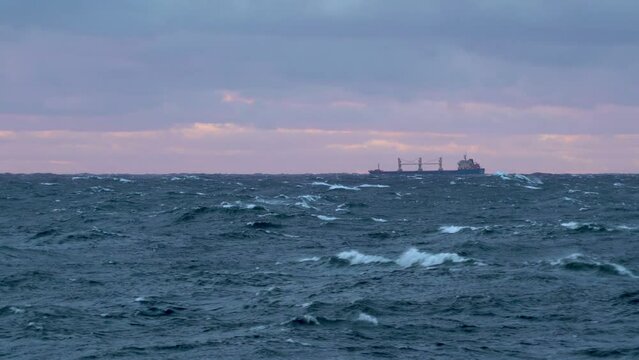 Ship in storm. Bulk carrier vessel on horizon, waves in foreground. Waves with white foam