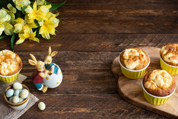 Easter cupcakes, chocolate eggs, ceramic bunnies and yellow flowers on the table