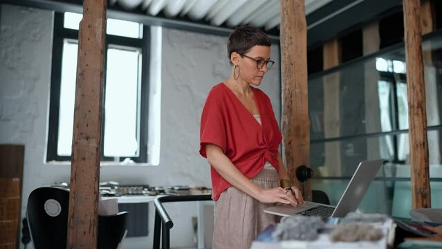 Positive brunette woman architect working on laptop in the office