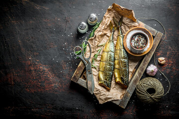 Smoked fish mackerel on a tray with twine, scissors and spices.