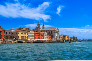 Blue sky over the sea and vintage houses along the Grand Canal in the city of Venice on a sunny day, the main sea street of Venice, architecture and sights of Italy, touristic European routes