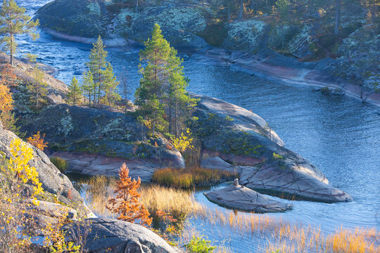 Ladoga skerries on the lake. A beautiful view of the rocky shores covered with pine trees. Nordic nature at sunset. Stunning view of islands and archipelago. National Park of Karelia