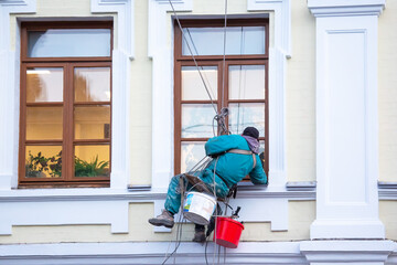 Fototapeta premium climber worker cleaning of windows and the facade of a renovated residential building. construction business industry
