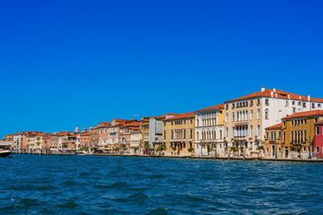 Airplane and seagulls in the blue sky over the sea and vintage houses along the Grand Canal in the city of Venice on a sunny day, the main sea street of Venice, architecture and sights of Italy