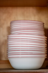 Narrow depth of field picture of an open kitchen cabinet stacked ceramic plates and bowls.