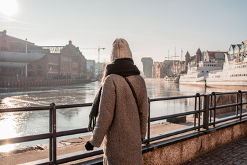 Woman enjoys the panorama of the city of Gdansk. Amazing scenic view of the city. The girl explores Poland, Europe. City and sea. Urban autumn landscape, old historical architecture
