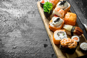 Set of different types of sushi and rolls on wooden cutting Board.