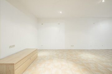 Living room of an empty house with light brown stoneware floors and a loose wooden cabinet