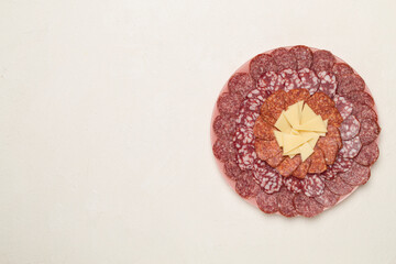Plate with different smoked meat and cheese on concrete background, top view