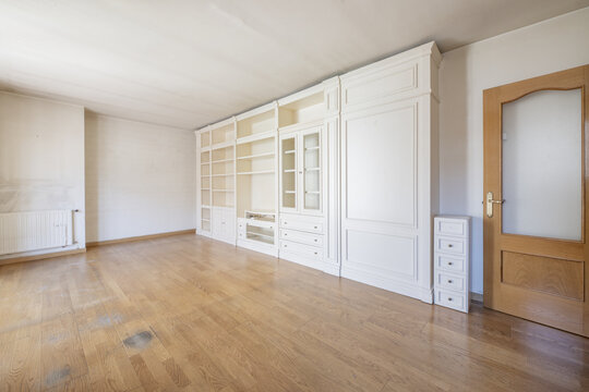 Living room of an empty house with oak doors and a custom-made white lacquered wooden bookcase