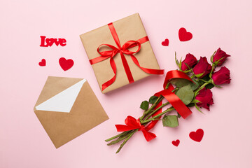 Valentines day gift box with red roses on color background, top view