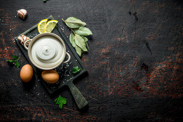 Mayonnaise in bowl on cutting Board with lemon slices, eggs and Bay leaf.