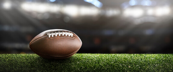 American football ball on the grass of a stadium