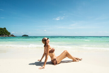 Fototapeta na wymiar Dream summer destination. Woman enjoying sunny tropical day and blue sky. Girl with tanned body.