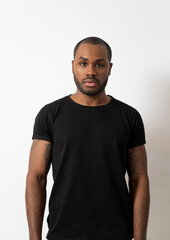 A photo of a portrait of a dark-skinned man posing in a black T-shirt on a white background, basic photo.