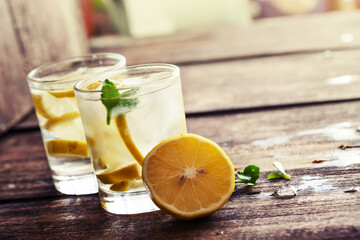 Glasses of water with lemon over rustic wooden background