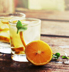 Glasses of water with lemon over rustic wooden background