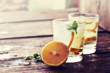 Glasses of water with lemon over rustic wooden background