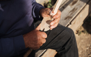 Hands carving spoon from wood, working with chisel close up. Process of making wooden spoon. Wooden workshop.