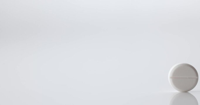 white tablet rolls through the frame, slow motion video