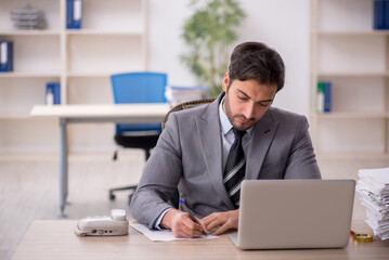 Obraz premium Young male employee and too much work in the office