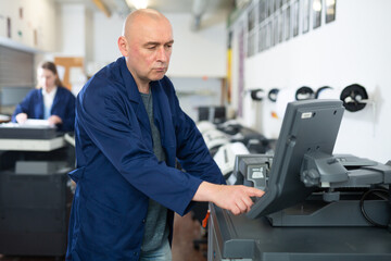 Naklejka na ściany i meble Printing house employee works on modern printing equipment