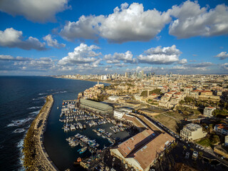 Aerial view of Ships anchoring at the Jaffa port in a cloudy day. tel aviv skyline with urban skyscrapers at the background