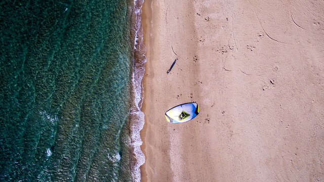 Vertical aerial view shot of a man walking with a twin tip board and a kite, preparing to kiteboarding at caesarea beach