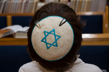 A rear view of praying young man with star of david, magen david, yarmulke