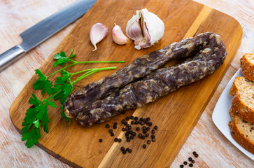 Traditional Spanish cured pork sausage on a wooden chopping board with garlic, peppercorns and a...