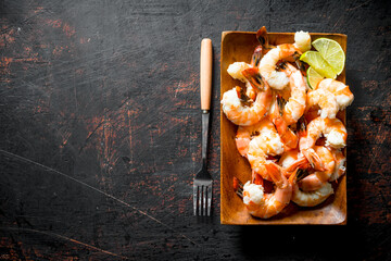 Fragrant shrimps on a wooden plate with a fork.