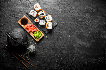 Delicious rolls with salmon and vegetables on a stone Board with soy sauce in bowl.