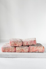 Pink lamingtons on a marble tray, Australian raspberry lamingtons, cake covered in desiccated coconuts