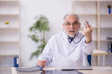 Old male doctor working in the clinic