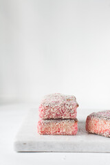 Pink lamingtons on a marble tray, Australian raspberry lamingtons, cake covered in desiccated coconuts