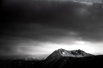 曇り空の下の雪を被った岩山のモノクローム。