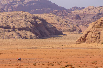 Fototapeta na wymiar Horsemen traveling the desert landscape of Wadi Rum in Jordan in the Middle East