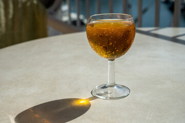 Drinking of French apple sparkling cider in glass on plastic table