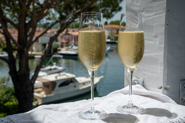 Drinking of French brut champagne sparkling wine in glasses in yacht harbour of Port Grimaud near Saint-Tropez, French Riviera vacation, France