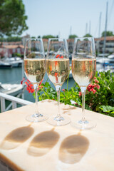 Drinking of French brut champagne sparkling wine in glasses in yacht harbour of Port Grimaud near Saint-Tropez, French Riviera vacation, France