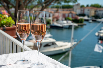 Drinking of French brut champagne sparkling wine in glasses in yacht harbour of Port Grimaud near Saint-Tropez, French Riviera vacation, France
