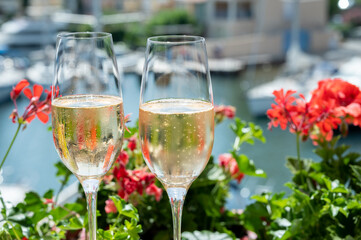 Drinking of French brut champagne sparkling wine in glasses in yacht harbour of Port Grimaud near Saint-Tropez, French Riviera vacation, France