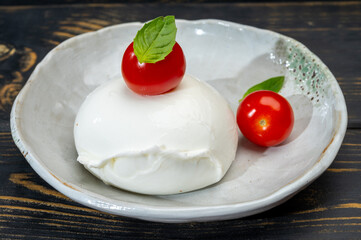 Сheese collection, one big ball on soft white italian mozzarella bufala cheese with red tomato and green basil leaves