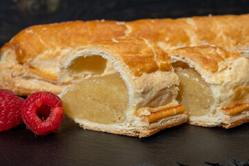 Fresh baked Dutch filled spicy cookies from puff pastry with almonds in autumn colors on dark stone
