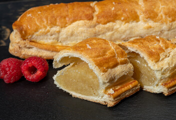 Fresh baked Dutch filled spicy cookies from puff pastry with almonds in autumn colors on dark stone