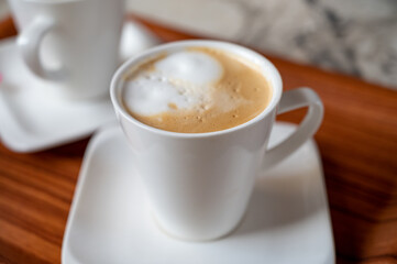 White cup of coffee latte served in outdoor cafe in France