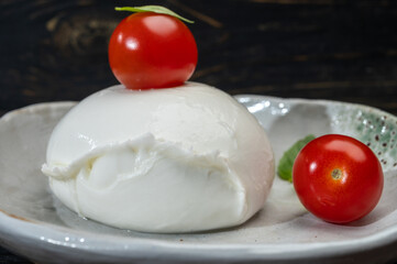 Сheese collection, one big ball on soft white italian mozzarella bufala cheese with red tomato and green basil leaves
