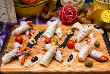 Obraz na płótnie Canvas spring rolls on a wooden board, beautifully decorated appetizers
