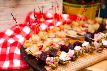 assorted canapés: skewer of beet cheese slice with mold and walnuts, skewer of duck breast meat with pineapple slice